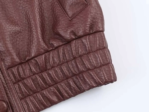 Detailed macro view of deep brown leather jacket with lychee texture and ribbed hem