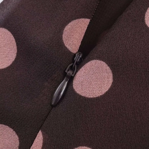 Detailed view of the invisible zipper on a brown polka dot chiffon fabric garment