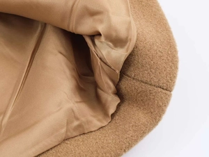 Detail view of double-layered camel wool coat showing smooth silk lining and premium texture