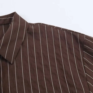 Détail d'une chemise rayée marron foncé avec lignes blanches verticales et col à revers