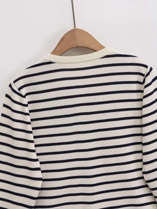Close-up of a striped knit cardigan with round neck on a wooden hanger for women
