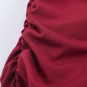Detailed macro view showing the deep red ruched fabric texture of the knit maxi dress
