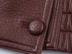 Macro shot of burgundy faux leather jacket featuring matching covered button and stitching