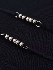 Macro shot of silver metal sphere ornaments on a black knitted halter neck top
