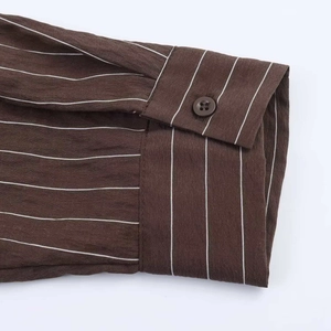 Détail du poignet d'une chemise marron à rayures blanches avec bouton classique