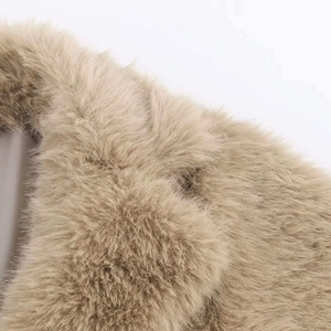 Close-up detail of beige faux fur coat texture with plush fibers and smooth grey inner lining