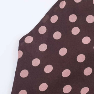 Detail of coffee brown chiffon fabric with large pale pink polka dots and smooth texture