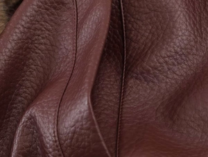 Macro shot of dark burgundy faux leather texture with high-quality double stitching detail