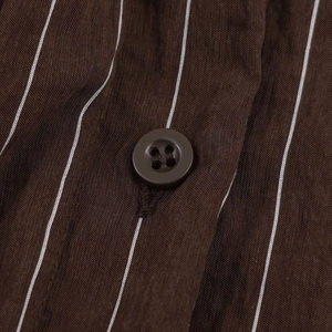 Vue macro de la texture du tissu rayé marron foncé et d'un bouton rond assorti