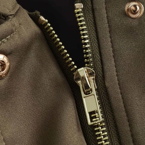 Army green bomber jacket detail showing gold zippers and embossed metal buttons