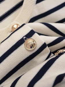 Detailed close-up of navy and cream striped knit cardigan with golden crest buttons