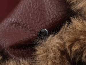 Detail of faux fur collar and textured dark brown leather jacket with a black button