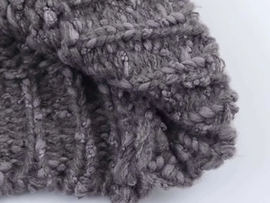 Close-up of grey cable knit texture with detailed flower embroidery and soft yarn