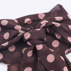 Detail of a brown polka dot chiffon halter top showing the delicate bow tie design