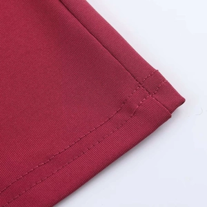 Close-up of double-needle hem stitching on dark red sleeveless pleated dress fabric