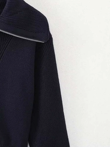 Détail d'un pull en maille côtelée bleu marine avec demi-zip argenté et texture épaisse