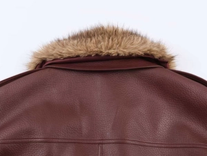 Detail of burgundy lychee-textured leather jacket featuring a brown faux fur collar accent