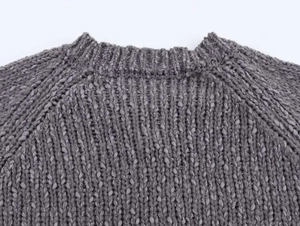 Close-up of dark grey thick knit sweater featuring chunky texture and raglan sleeves
