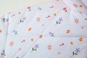 Nahaufnahme der weißen wattierten Jacke mit kleinen rosa und lila Blumenmustern