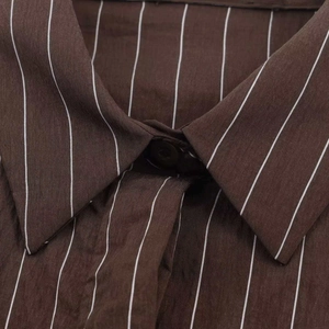 Détail du col d'une chemise à rayures verticales marron avec texture fine et bouton visible