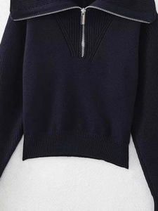 Détail d'un pull en maille marine avec texture côtelée et col demi-zippé argenté