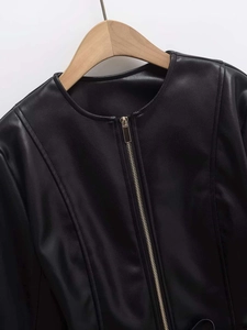 Detail of the round neckline and golden zipper closure on a black faux leather jacket