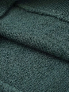 Macro detail of high-quality dark green knitted fabric showing warm wool texture and fibers