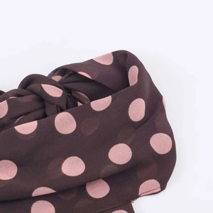 Detail of coffee brown chiffon fabric with pink polka dots and soft texture finish