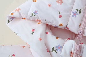 Detail der geblümten Kapuzenjacke für Mädchen mit rosa Reißverschluss und Füllung