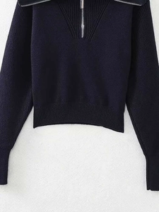 Détail d'un pull en maille bleu marine avec col montant zippé et poignets côtelés