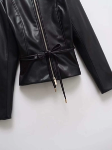 Detail of slim-fit black faux leather jacket with waist belt and silver zipper closure