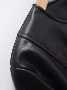 Detail shot of the faux leather texture on collar and shoulder of the black jacket