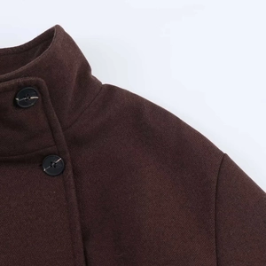 Detail of dark brown wool coat collar with stand-up design and large black button
