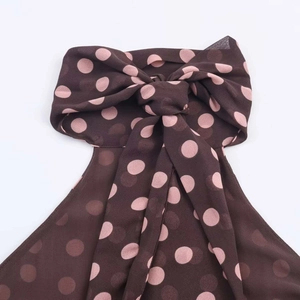Detail of halter neck top with large pink polka dot bow on dark brown chiffon fabric