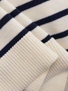 Close-up of cream and navy striped knit fabric with detailed ribbed texture and stitching