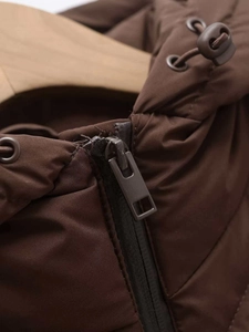 Close-up of metal zipper and drawstring hood on brown quilted winter jacket