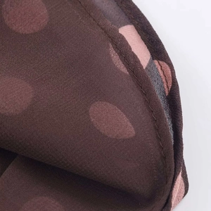 Detail of dark brown polka dot chiffon fabric with high-quality hemmed edge stitching