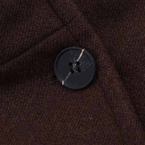 Detail of dark brown wool coat showing thick textured fabric and marble-effect button