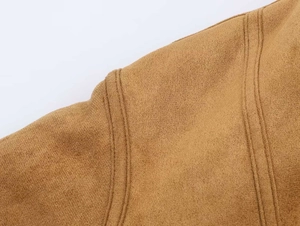 Gros plan détaillé du tissu en daim marron avec double couture précise sur l'épaule de veste
