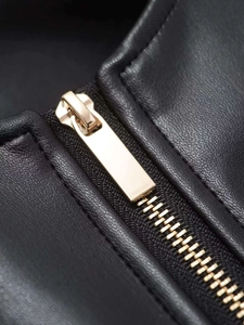 Detail of high-quality black faux leather texture and polished gold metal zipper on a jacket