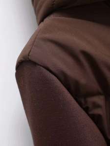 Detail of shoulder stitching and windproof brown quilted fabric on winter puffer jacket