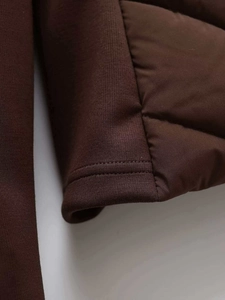 Close-up of the quilted fabric texture and neat double-needle stitching on the brown jacket