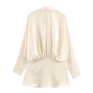 Detail view of cream satin dress featuring pleated waist and elegant silk-like texture
