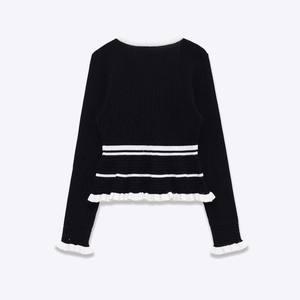 Women's black long sleeve knit sweater with white ruffle trim and peplum waist hem