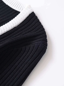 Detail of black ribbed knit sweater featuring contrasting white trim and textured fabric