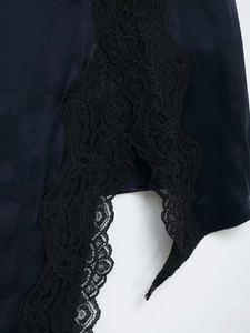 Detailed shot of black satin skirt hem featuring delicate floral lace embroidery and side slit