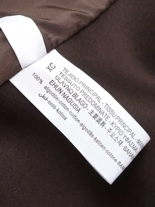 Macro view of white satin fabric care label with 100% cotton composition details