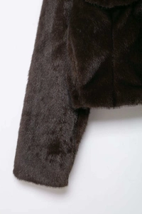 Detail showing the thick texture and glossy finish of the brown faux fur jacket fabric