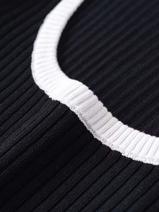Close-up detail of contrast rib-knit neckline and textured black vertical rib fabric