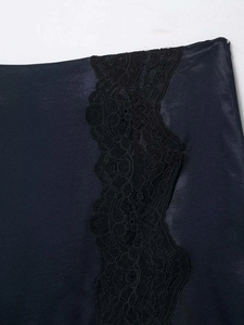 Détail de la matière en satin noir avec dentelle florale délicate et fente latérale